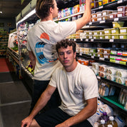 Two men in a grocery store aisle with shelves stocked with products.